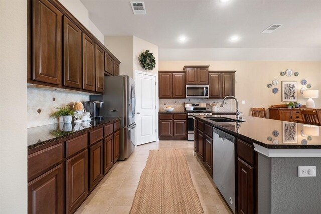 kitchen with sink, stainless steel appliances, dark brown cabinets, and tasteful backsplash