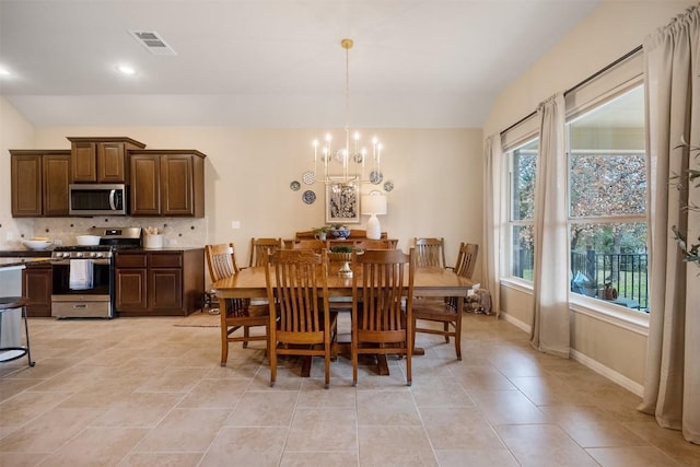 tiled dining area featuring lofted ceiling, a notable chandelier, and plenty of natural light