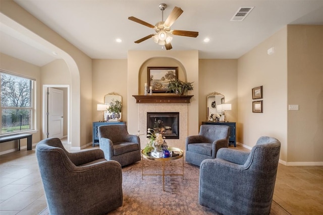 living room featuring a tile fireplace and ceiling fan