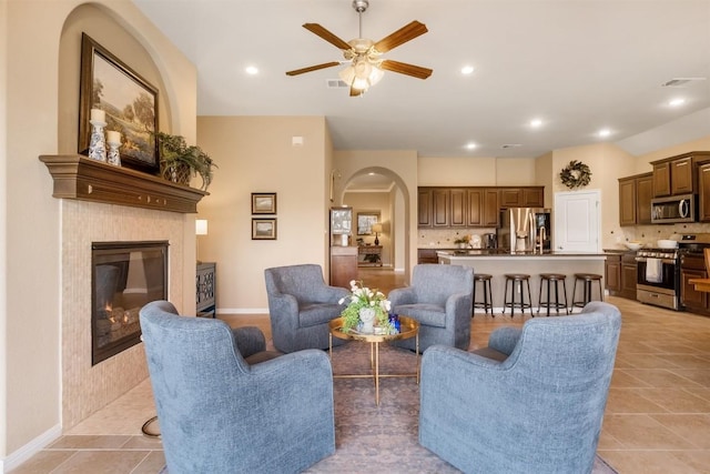 living room with a fireplace, ceiling fan, and light tile patterned floors