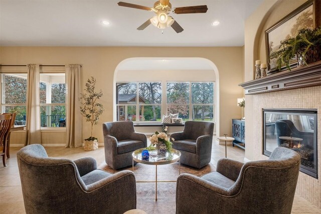 tiled living room with a fireplace, ceiling fan, and a healthy amount of sunlight