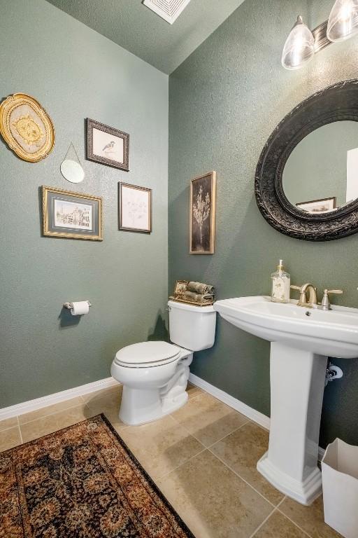 bathroom with toilet, tile patterned flooring, and a textured ceiling