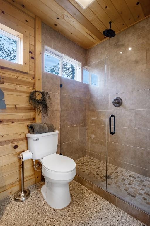 bathroom featuring toilet, an enclosed shower, and wooden ceiling