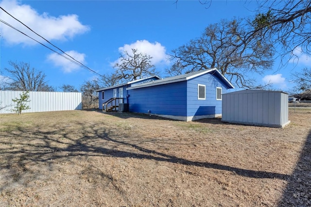 rear view of house with central AC unit and a storage unit