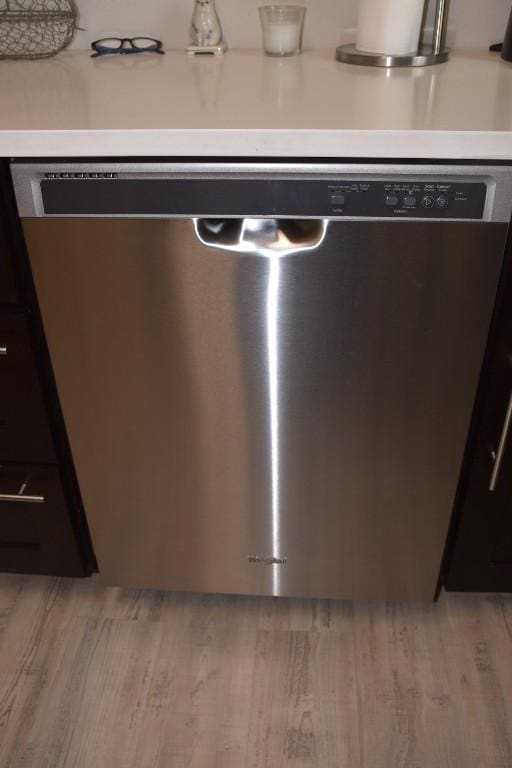 room details with light hardwood / wood-style flooring and stainless steel dishwasher