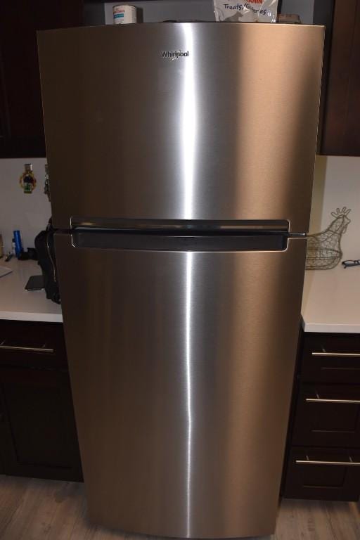 details with light hardwood / wood-style floors, stainless steel fridge, and dark brown cabinetry