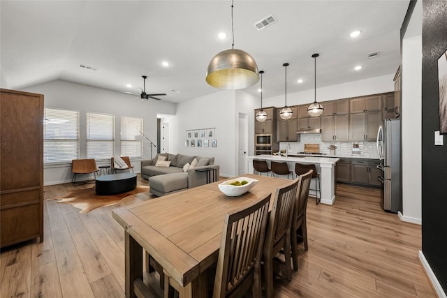 dining space with ceiling fan, sink, vaulted ceiling, and light wood-type flooring