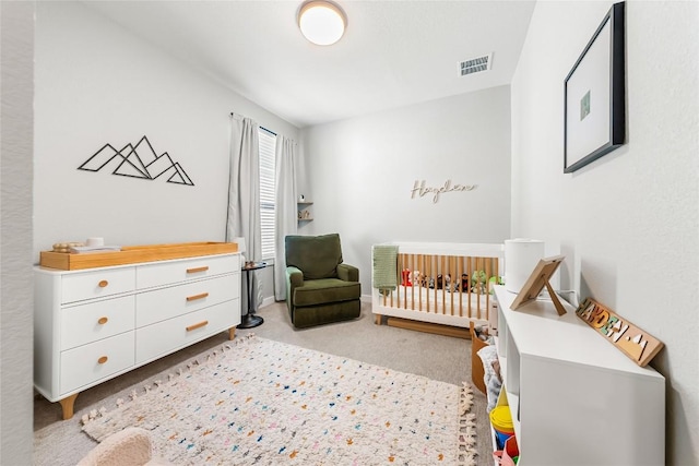 bedroom with light carpet and a nursery area