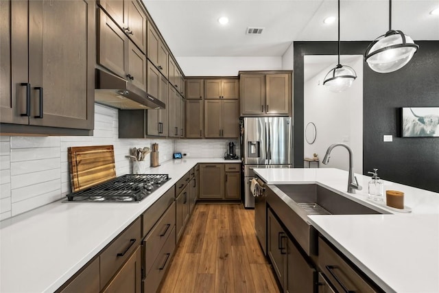 kitchen featuring sink, stainless steel appliances, dark hardwood / wood-style flooring, decorative light fixtures, and decorative backsplash