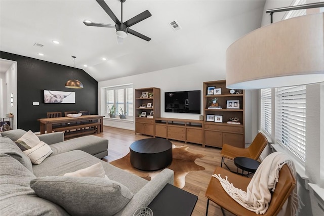 living room featuring ceiling fan, lofted ceiling, and light wood-type flooring