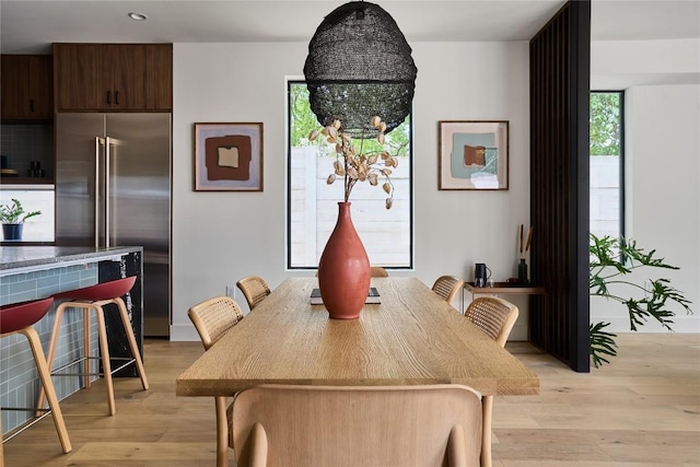 dining area with a wealth of natural light, light hardwood / wood-style floors, and a notable chandelier