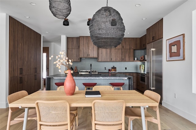 kitchen featuring sink, wall oven, light hardwood / wood-style floors, decorative backsplash, and stainless steel built in fridge