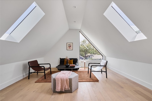 living area featuring light wood-type flooring and vaulted ceiling with skylight