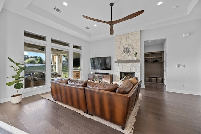 living room featuring ceiling fan, dark hardwood / wood-style flooring, a fireplace, and a tray ceiling