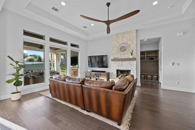 living room with ceiling fan, a fireplace, dark hardwood / wood-style flooring, and a raised ceiling