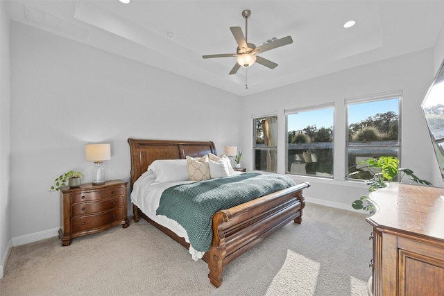 carpeted bedroom with a tray ceiling and ceiling fan