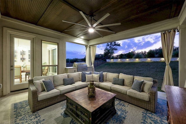 patio terrace at dusk featuring an outdoor hangout area, a grill, and exterior kitchen