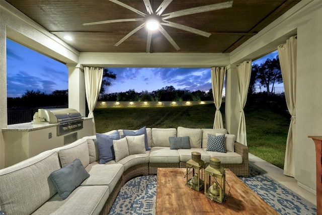 patio terrace at dusk with an outdoor kitchen, grilling area, and ceiling fan