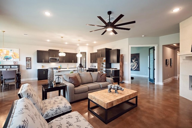 living room with sink and ceiling fan with notable chandelier