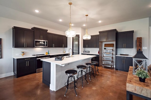 kitchen featuring a kitchen breakfast bar, stainless steel appliances, a kitchen island with sink, sink, and pendant lighting