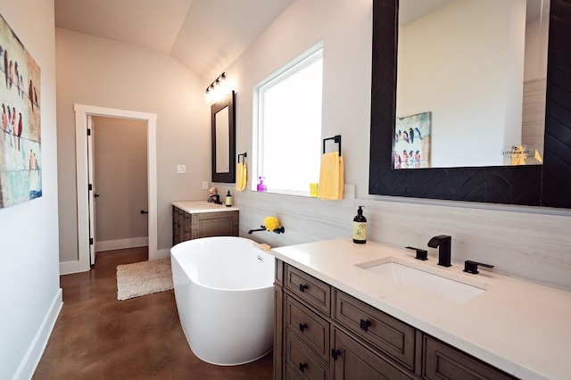 bathroom with concrete flooring, vanity, vaulted ceiling, and a bathing tub