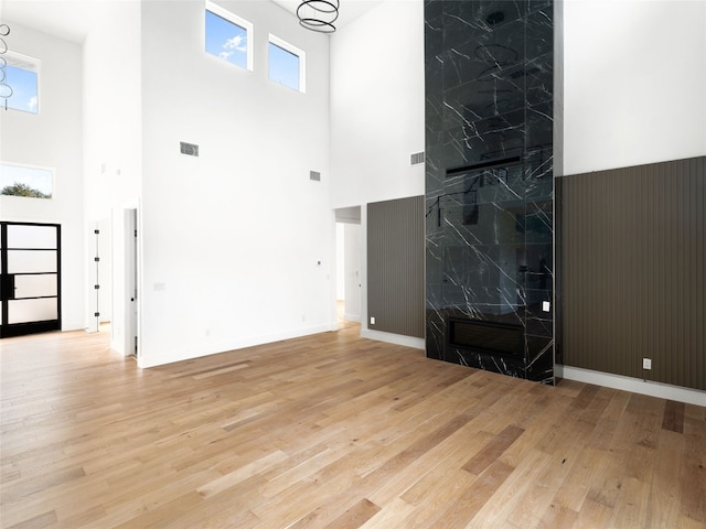 unfurnished living room with light wood-type flooring and a towering ceiling