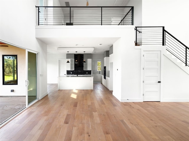 unfurnished living room with a high ceiling, light hardwood / wood-style flooring, and plenty of natural light