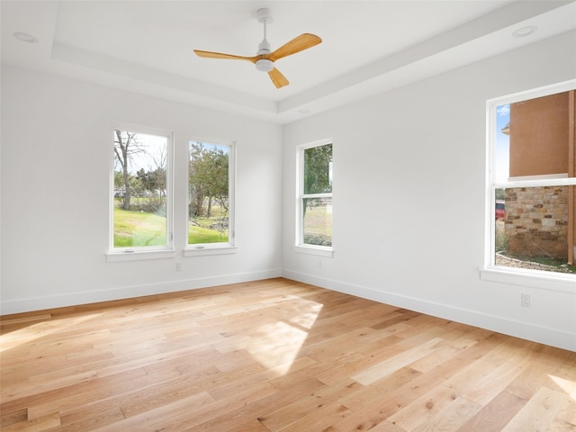 unfurnished room with ceiling fan, a raised ceiling, and light wood-type flooring