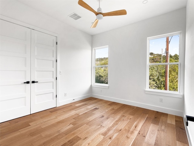 unfurnished bedroom with multiple windows, ceiling fan, a closet, and light wood-type flooring