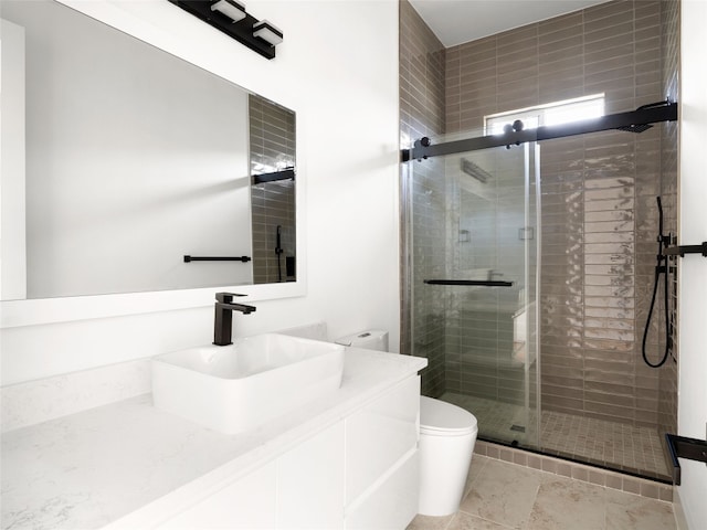 bathroom with vanity, toilet, and a shower with door