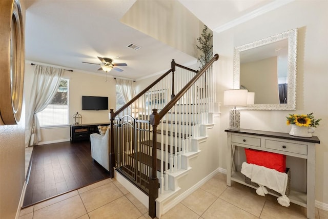 stairs with crown molding, tile patterned flooring, and ceiling fan