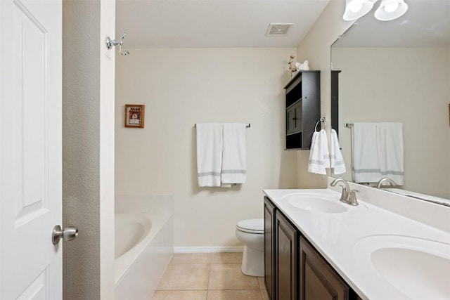 bathroom featuring tile patterned floors, vanity, toilet, and a tub to relax in