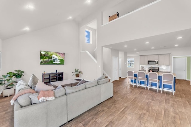 living room featuring light wood-type flooring and high vaulted ceiling