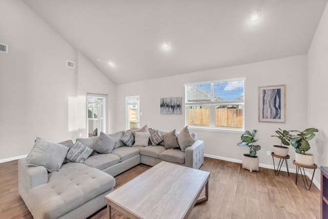 living room featuring light wood-type flooring and high vaulted ceiling