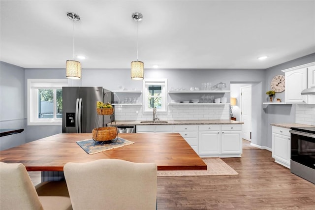 kitchen featuring sink, a healthy amount of sunlight, hanging light fixtures, white cabinets, and appliances with stainless steel finishes