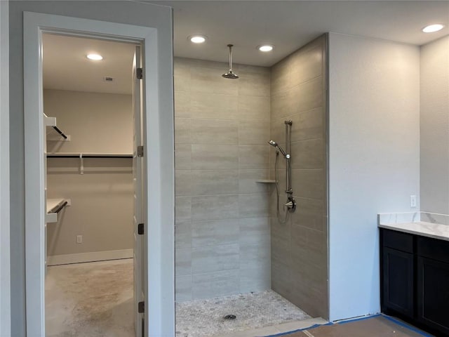 full bathroom with a tile shower, recessed lighting, a spacious closet, and baseboards