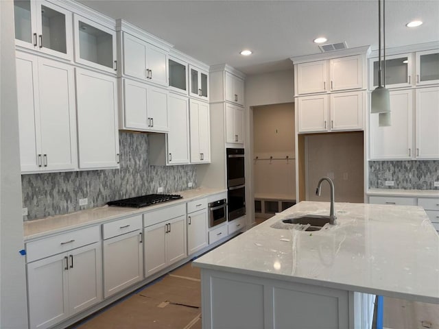 kitchen with stainless steel gas cooktop, a sink, white cabinets, and light stone countertops