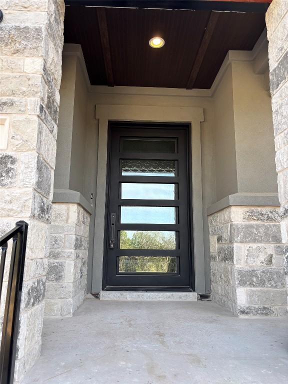 doorway to property with stone siding and stucco siding