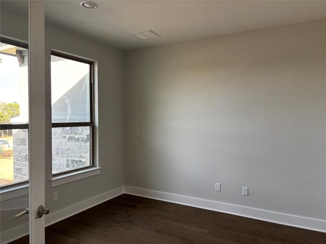 unfurnished room with dark wood finished floors, visible vents, and baseboards