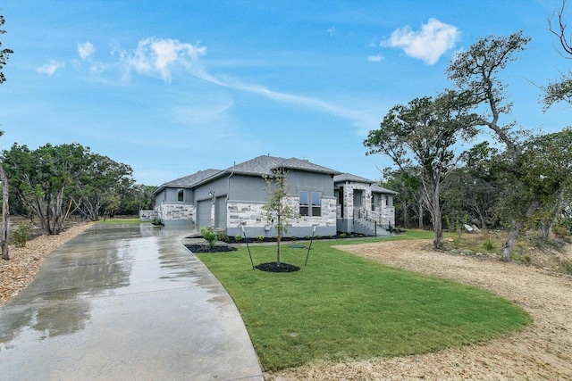 4616 Destination Way, Jonestown, TX 78645 - view of front of house with driveway, a front lawn, an attached garage, stone siding, and stucco siding