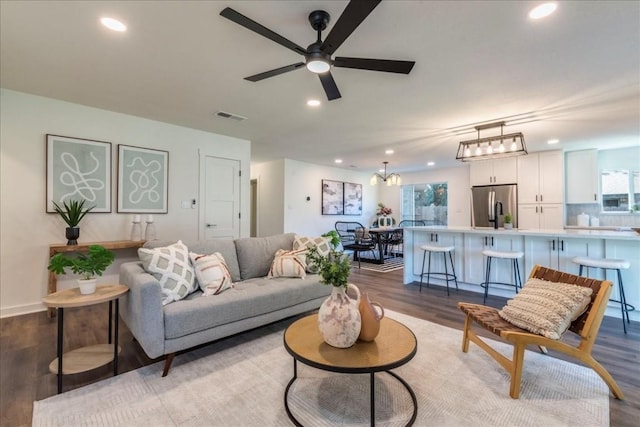 living room featuring wood-type flooring and ceiling fan with notable chandelier