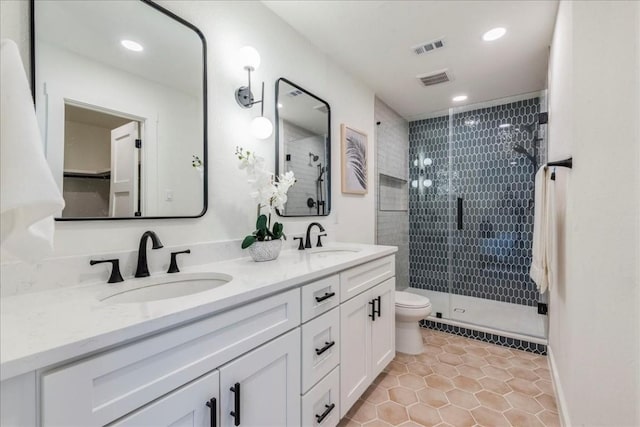 bathroom featuring tile patterned flooring, vanity, toilet, and a shower with shower door