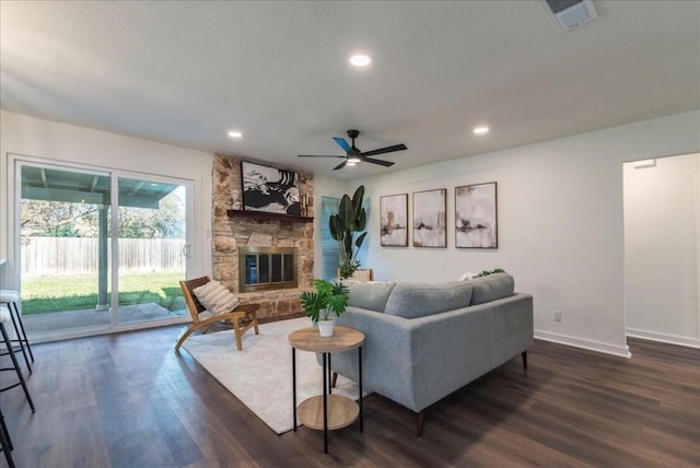 living room featuring ceiling fan, a fireplace, and dark hardwood / wood-style floors