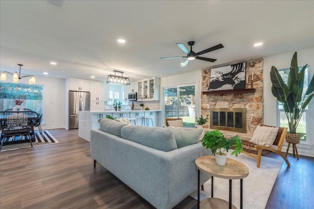 living room featuring a fireplace, ceiling fan, sink, and dark wood-type flooring