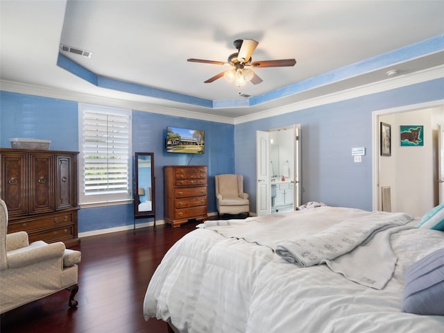 bedroom featuring dark hardwood / wood-style flooring, a tray ceiling, ensuite bath, and ceiling fan