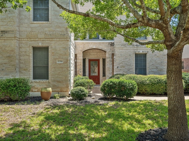 view of exterior entry featuring a lawn