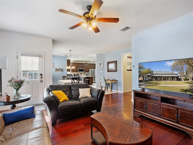 living room with ceiling fan and dark wood-type flooring