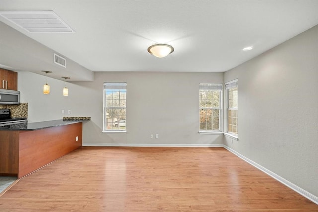 kitchen with light hardwood / wood-style floors, hanging light fixtures, black range with electric cooktop, and tasteful backsplash