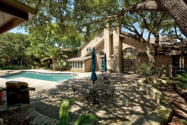 view of pool featuring a jacuzzi, a patio, and area for grilling