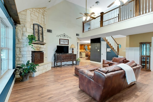 living room featuring hardwood / wood-style flooring, a towering ceiling, a fireplace, and a wealth of natural light